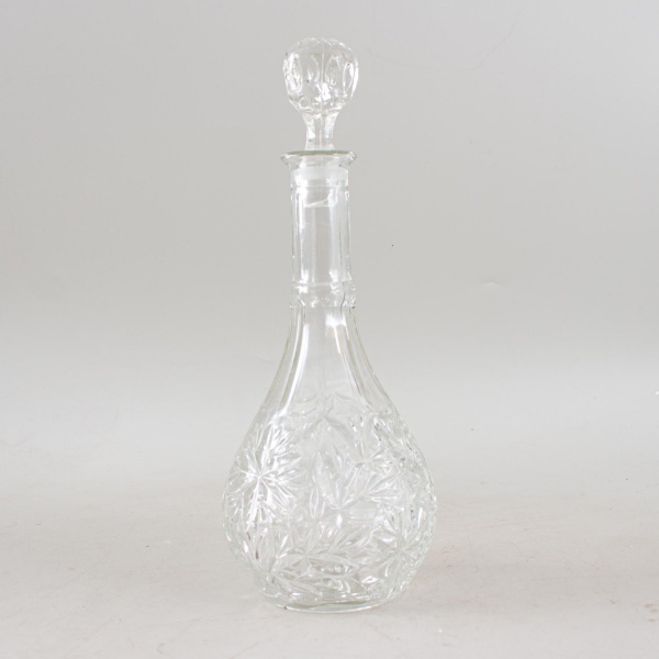 Licoreira em cristal incolor ricamente lapidado, com bojo de formato bojudo decorado por motivos florais e geométricos, gargalo alongado e tampa original facetada, evidenciando excelente acabamento e