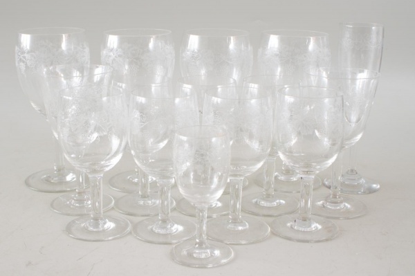Lote composto por 15 taças em cristal, todas com decoração gravada de flores e cachos de uva, medindo a maior 18 cm de altura, apresentando bicados e marcas de uso.