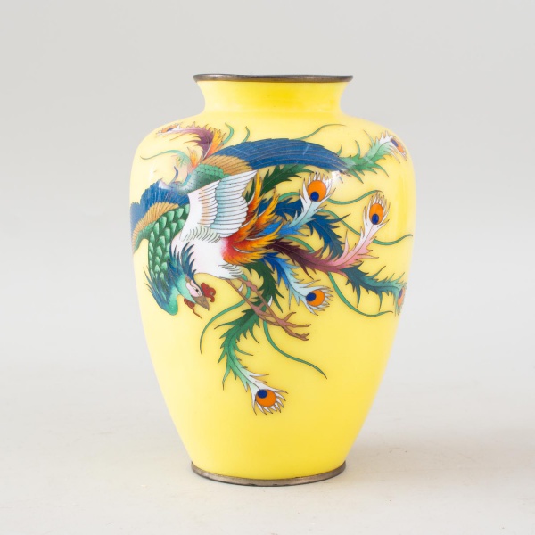 Vaso em porcelana esmaltada na cor amarela, decorado com ave do paraíso e folhagens em policromia, com borda metálica, medindo 19 cm de altura, apresentando marcas do tempo e desgastes compatíveis com