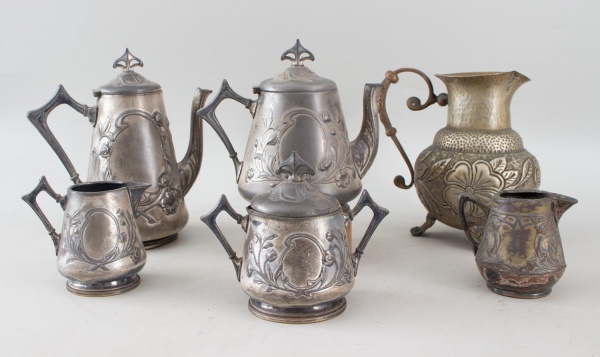 Lote composto por cafeteiras, leiteiras e jarras em metal branco, com decoração em relevo de motivos florais e arabescos, incluindo exemplar com corpo martelado, de estilos e modelos variados. Altura