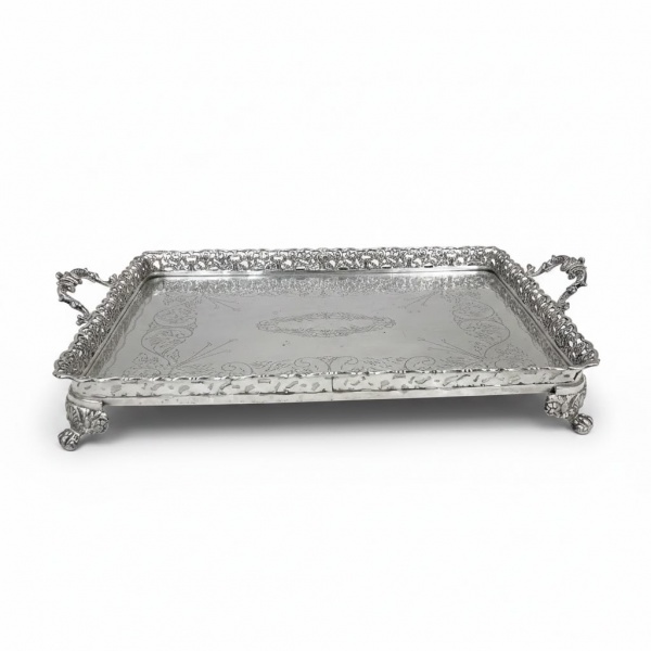 Bandeja retangular em prata de baixo teor, com borda vazada em rico trabalho rendilhado, alças laterais e pés ornamentados, superfície gravada com decoração em arabescos. Medidas: 48 x 31 cm. Peso: 1.