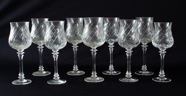 Conjunto com nove taças em cristal incolor do mesmo modelo, com rica decoração lapidada em espiral. Altura da maior: 20 cm. Apresentam marcas de uso, bicados e desgastes compatíveis com o tempo.