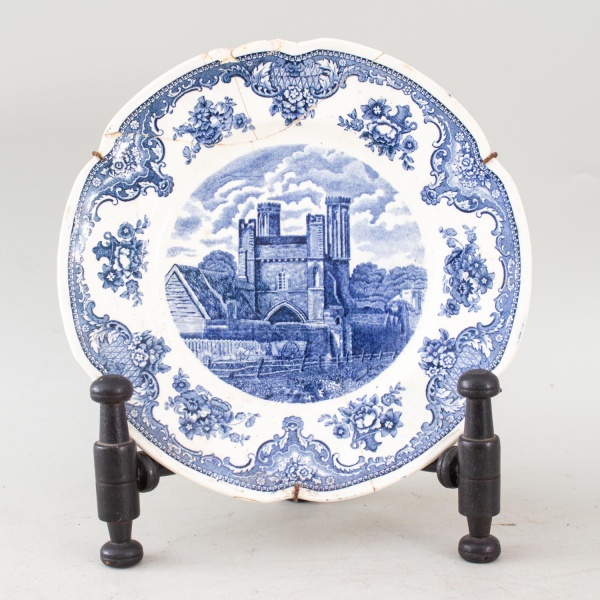 Prato decorativo em porcelana brasileira, marca São Caetano, com decoração em azul sob esmalte representando paisagem arquitetônica e borda floral. Medida: 23 23 cm. Apresenta quebra colada, grampos m