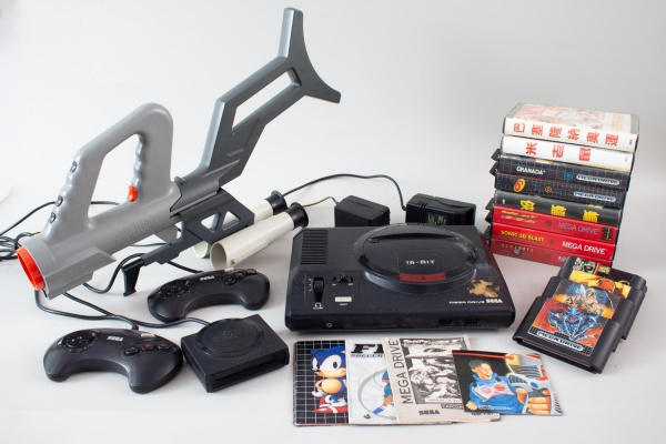 Lote contendo console Sega Mega Drive 16-Bit com controles, cabos, acessórios e jogos diversos, incluindo cartuchos e caixas de jogos como Mortal Kombat, Batman e outros conforme fotos. Acompanha aces