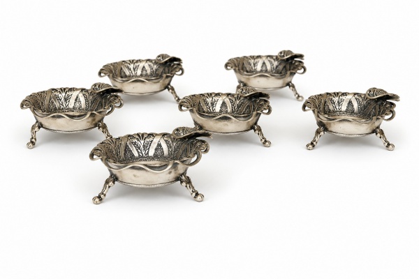 Conjunto de seis pequenos cinzeiros em prata teor 900, com suporte em moedas brasileiras de 1000 réis, possuindo bordas decoradas em relevo e três pés de apoio, medindo 2 cm de altura cada, com peso t