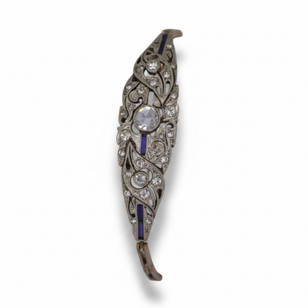 Pulseira em ouro 18K, com elemento central em desenho vazado de inspiração Art Déco, adornado por pedras incolores e detalhes em pedras azuis de lapidação calibrada, com elos articulados e fecho de se