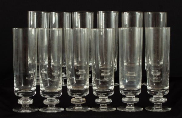 Lote com 12 taças em cristal incolor, de formato cilíndrico com haste curta e base circular, altura de 16 cm, apresentando marcas e contém bicados.