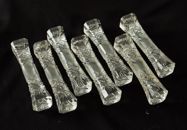 Lote com 7 descansos para talheres em cristal lapidado, com decoração geométrica e floral em lapidação, medindo 9 cm de comprimento, apresentando marcas do tempo.