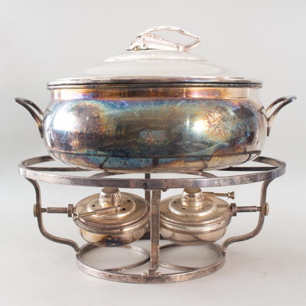 Rechaud em metal espessurado a prata, composto por recipiente com tampa, suporte e dois queimadores, com pega em formato de vegetal na tampa, medindo 36 cm de altura e 43 cm de diâmetro, apresentando