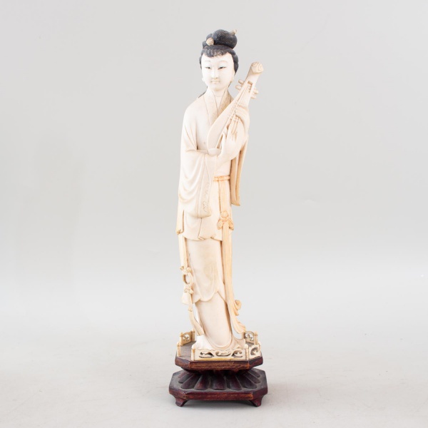 Escultura chinesa em marfim, representando dama trajando vestes típicas e portando instrumento musical de cordas, com delicado leve policromado e base em madeira entalhada, medindo 31 cm de altura, ap