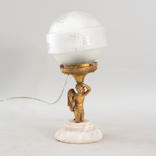 Luminária de mesa em estilo Art Déco, composta por estatueta de Eros em petit bronze sobre base de alabastro, com globo difusor em vidro fosco de desenho geométrico original, medindo 33 cm de altura,