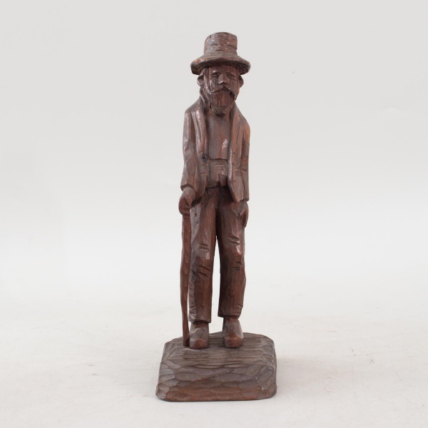 Escultura chilena em madeira nobre entalhada, representando humilde camponês apoiado em bengala, com expressiva fisionomia e base integrada, assinada na base, medindo 22 cm de altura, apresentando mar