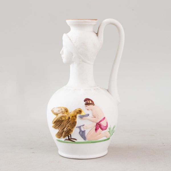 Ânfora decorativa em biscuit branco, inspirada nas lécitos gregas do século XIX, modelada em forma de busto feminino com alça posterior, decorada em relevo policromado representando jovem alimentando