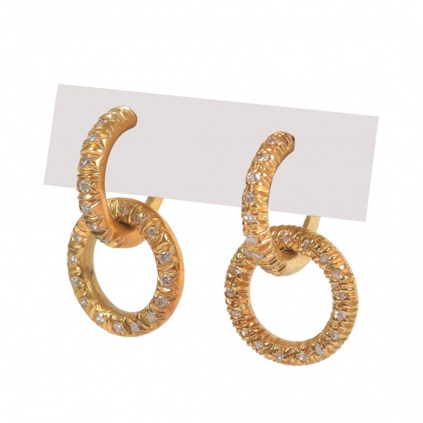 Par de brincos em ouro 18K, design composto por dois aros entrelaçados, um deles cravejado com pequenas pedras claras, fecho de alavanca. Peso total: 5,5 g.