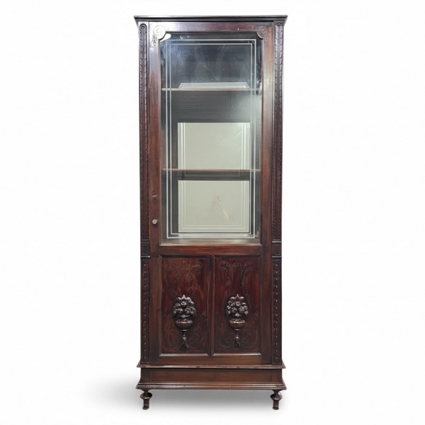 Cristaleira antiga em madeira nobre, com porta superior envidraçada, prateleiras internas, espelho ao fundo, entalhes decorativos em relevo e pés torneados, medindo 220 cm de altura, 52 cm de profundi