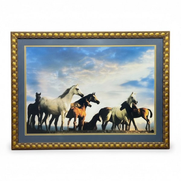 Reprodução artística emoldurada representando grupo de cavalos em paisagem sob céu aberto, protegida por vidro e acondicionada em moldura de madeira com acabamento dourado e paspatur azul, medindo 89