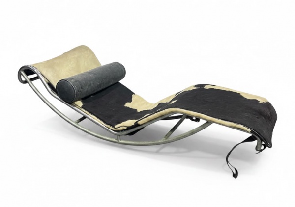 Chaise longue de estilo moderno, com estrutura tubular metálica, estofamento revestido em couro natural com pelo bovino nas cores preta e branca e apoio cilíndrico para cabeça, medindo 42 cm de altura