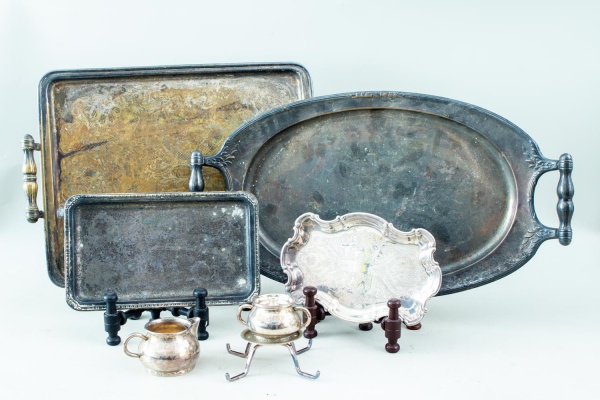 Lote composto por 6 peças em metal prateado, sendo 4 bandejas e travessas de servir de formatos variados, 1 cremeira e 1 açucareiro com tampa, medindo a maior bandeja 41 x 31 cm, apresentando marcas d