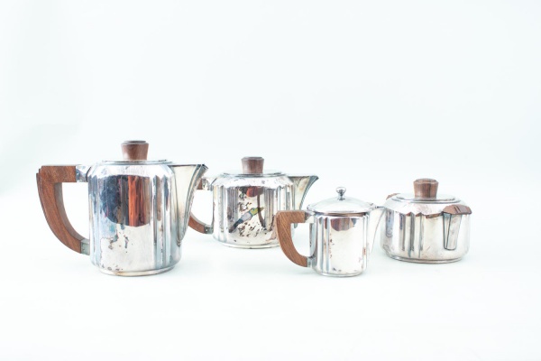 Conjunto para café e chá da marca Christofle, composto por 4 peças em metal prateado, sendo cafeteira, chaleira, açucareiro com tampa e leiteira, com detalhes em madeira nas alças e puxadores, medindo