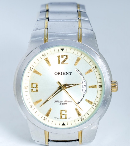 Relógio de pulso masculino Orient, original, com caixa e pulseira em aço inox bicolor, acabamento dourado, mostrador prateado com marcadores dourados, calendário retrógrado, resistência à água de 50 m