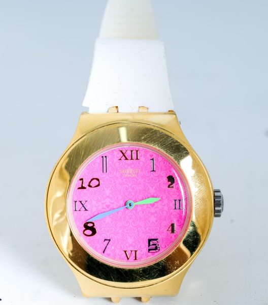 Relógio de pulso Swatch Irony, original, com caixa em aço inox com acabamento dourado, mostrador rosa com numerais estilizados e ponteiros coloridos, pulseira em silicone branca, movimento suíço, resi