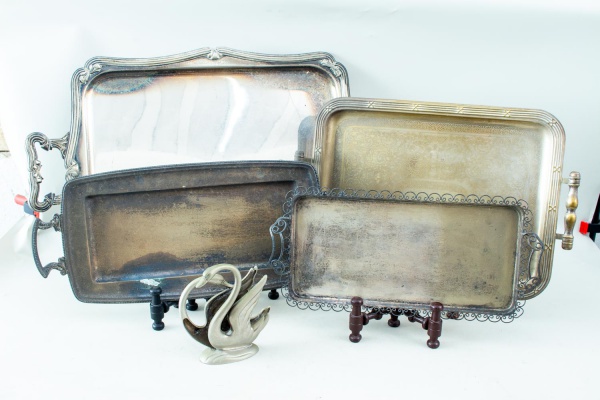 Lote composto por 5 peças, sendo 4 bandejas em metal prateado de formatos e tamanhos variados e 1 centro de mesa em vidro artístico, medindo a maior bandeja 50 x 40 cm, apresentando marcas do tempo, d