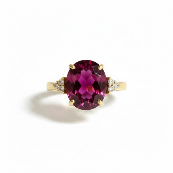 Anel em ouro amarelo 18k, pesando aproximadamente 5,83 g. Apresenta rodólita central em lapidação oval com peso aproximado de 4,00 ct, acompanhada de brilhantes que totalizam cerca de 0,18 ct. aro 14.