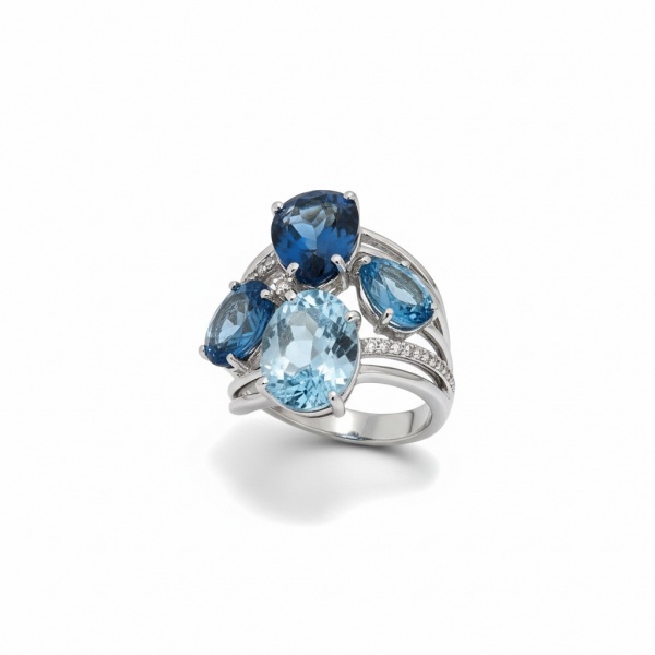 Quatro pedras de topázio azul em cortes variados (pera e oval), apresentando gradiente de tons London Blue, Swiss Blue e Sky BlueDiamantes brancos cravejados em pavê ao longo do aro e entre as pedras.