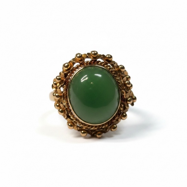 Anel em ouro amarelo com cabochão oval de esmeralda ao centro, moldura em cordão trançado e bordadura ornamental com esferas e floretes em ouro. Design vintage.Peso: 6,8 g | Aro: 16