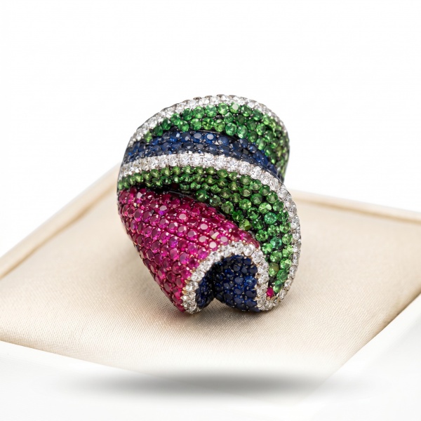 ANEL DE OURO 18K COM DESIGN CONTEMPORÂNEO CRAVEJADO COM MIX DE PEDRAS NAS TONALIDADES VERDE, AZUL E RUBI, HARMONIOSAMENTE CONTORNADAS POR DELICADOS BRILHANTES.Peso 14.1g AU 18k ARO: 17