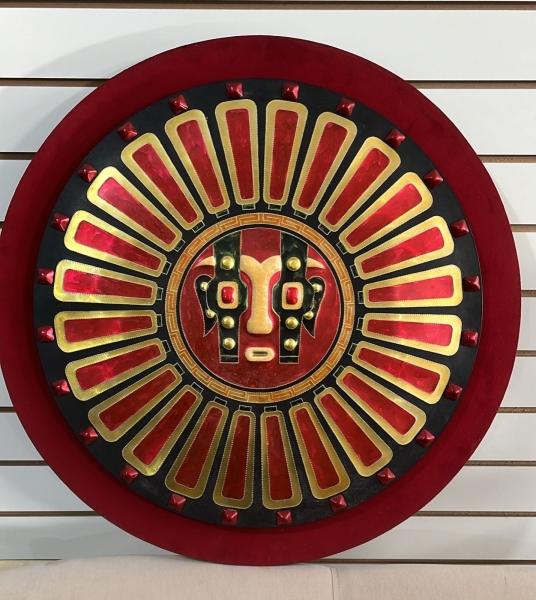mandala em metal repuxado e esmaltado em alto relevo, uma obra assinada pelo premiado artista Fernando Barreiros, com histórico de medalhas de ouro na década de 70. A peça apresenta uma máscara solar