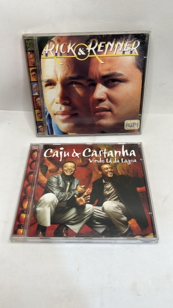 Lote com dois CDs de música brasileira composto pelo álbum da dupla sertaneja Rick e Renner e o álbum Vindo Lá da Lagoa dos repentistas Caju e Castanha. Os discos apresentam clássicos do sertanejo e d