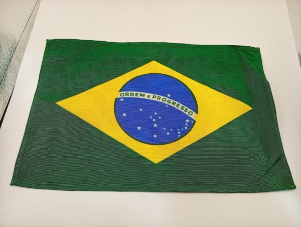 Bandeira do Brasil em tecido com estampa centralizada, peça decorativa com as cores verde, amarela e azul, ideal para colecionadores ou decoração de ambientes temáticos. Medidas aproximadas de 32 x 21