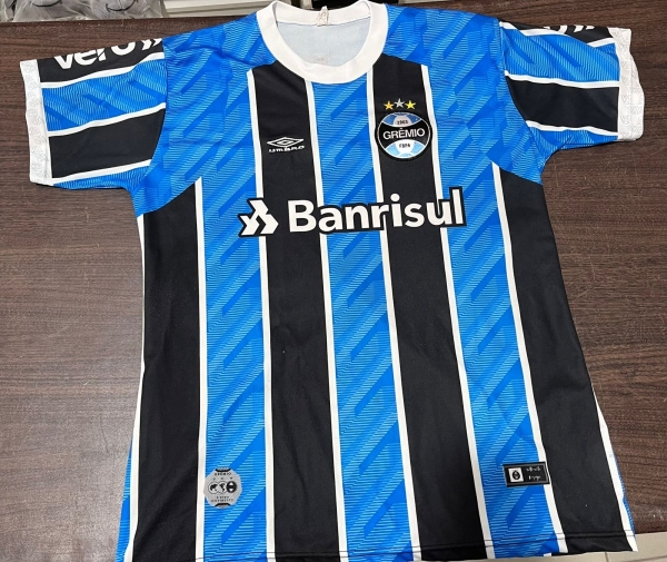 Camisa Paralela de Futebol do Grêmio Foot-Ball Porto Alegrense em Poliéster com Listras Verticais nas Cores Azul, Preto e Branco, Modelo com Número 10 e Patrocínios Banrisul, Uber, Laghetto e Unimed.