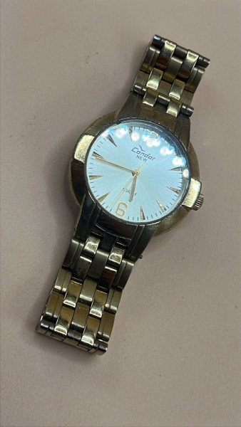Relógio de pulso masculino da marca Condor, linha New, com resistência de 10 ATM. Possui caixa dourada de aproximadamente 35mm de diâmetro, mostrador prateado com numeração 6 e 12, e pulseira em aço d
