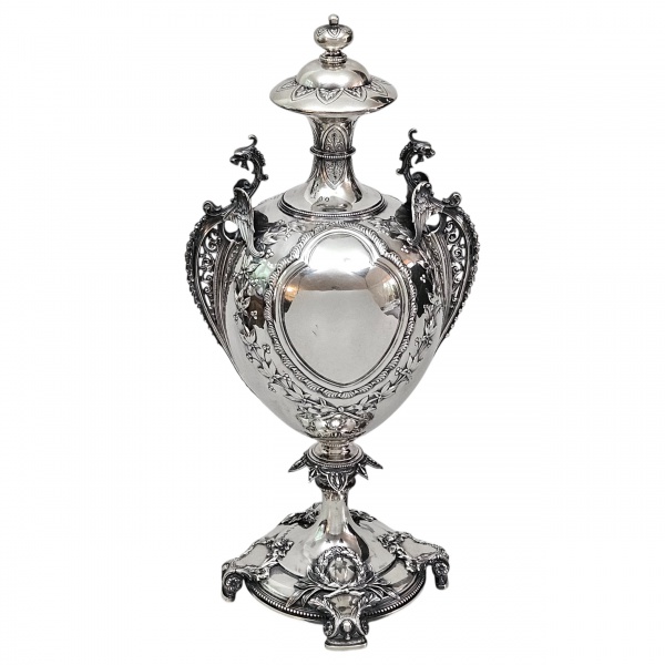 Magnífica ânfora de prata inglesa, teor 925, período Vitoriano, circa 1897-1898, cinzelagem manual profunda, marca da ourivesaria Hilliard & Thomazon. Apresenta pedestal com guirlandas, escalonado, bo