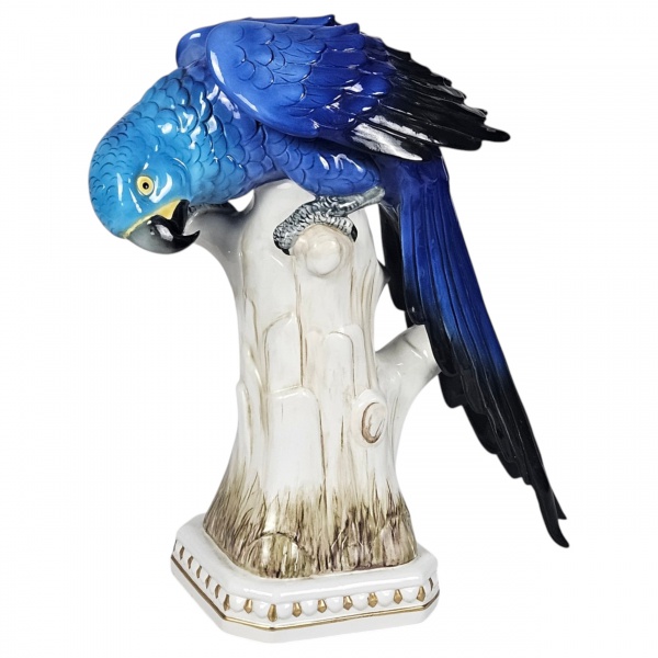 Bela arara azul, pousada sobre tronco, de porcelana alemã ENS, data provável da manufatura entre 1960 a 1980, estilo naturalista, trabalho muito detalhado nas penas e nos movimentos da ave. Esmaltação