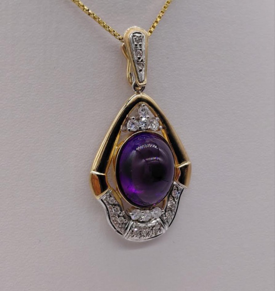 Pingente de ouro 18 k com ametista cabochão,7 diamantes de 4,7 pontos cada e 12 de 1 ponto aproximadamente. Peso de 9,6 gr. Comprimento de 4,5 cm.