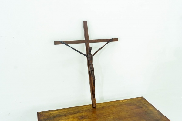 BRASIL - Crucifixo de parede em jacarandá, com representação estilizada de Cristo esculpida em madeira e sobreposta à cruz. Déc. 1960. Apresenta desgastes condizentes com o tempo. Dimensões: A 54 cm x