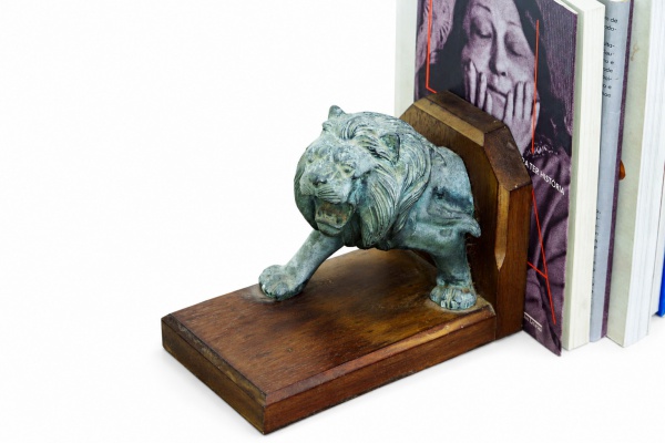 BRASIL - Par de serre-livres (suporte para livros) em madeira nobre, ornamentado com imponente figura esculpida em formato de leão em metal dividida entre as duas peças, compondo uma escultura complet