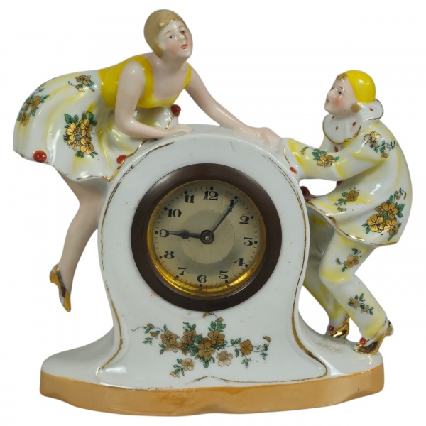 Relógio de mesa de porcelana alemã art decô, encimado com as figuras de Pierrot e Colombina. 18 x 17 x 6 cm. (No estado).