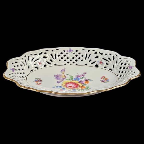 Fruteira em forma de bowl em porcelana branca esmaltada com sua borda fenestrada e ricamente decorado com motivos florais policromados. Marcas no verso da manufatura Bavária. Alemanha, séc. XX. (Novo,