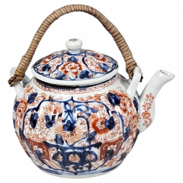 Pequena chaleira com sua tampa, de porcelana japonesa Imari, séc. XX, decoração característica com esmates rouge de fer e azul cobalto. Formato bojudo, corpo em gomilados, alça de lado a lado de vime.