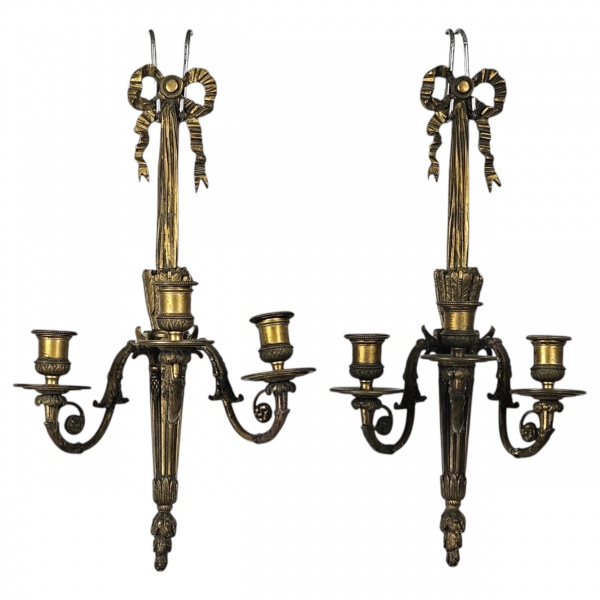 Par de arandelas ou apliques de parede francesas, estilo Luís XVI, confeccionadas em bronze cinzelado e dourado; projetadas para três braços de luz (velas ou lâmpadas), o topo central traz o clássico