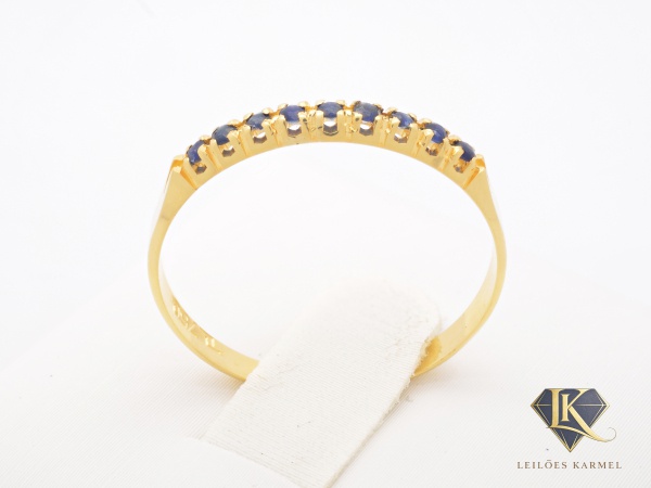 Meia Aliança em Ouro Amarelo 18K com Safiras Azul, Aro 18, peso de 1.1 gramas. Acompanha Certificado de Garantia Leilões Karmel.