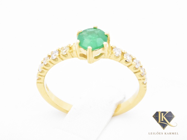 Anel Tipo Solitário em Ouro Amarelo 18K com Esmeralda de 4.8mm e 20 Pontos de Diamantes, Lapidação: Brilhante, Cor: JK e Pureza: VS2, Aro 16,5, peso de 2,2 gramas. Acompanha Certificado de Garantia Le