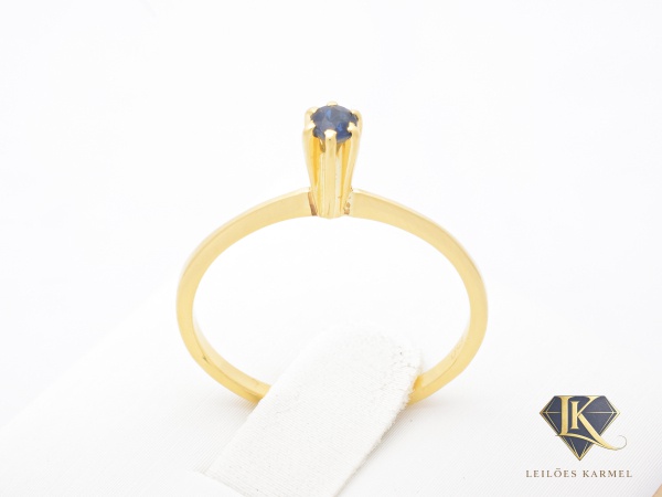 Anel Solitário em Ouro Amarelo 18K com Safira Azul, Aro 15, peso de 1.3 gramas. Acompanha Certificado de Garantia Leilões Karmel.