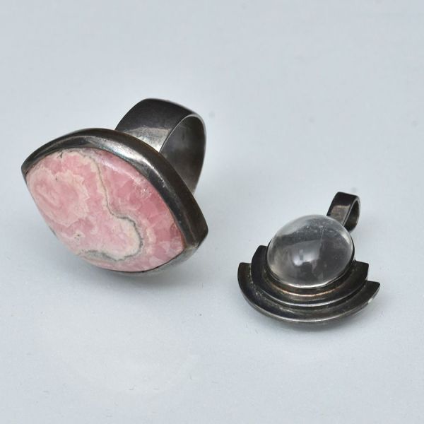 Anel em prata, tendo em sua parte principal pedra rodocrosita em formato de "olho", medindo 2,7 x 2,0 cm. Aro 13/14. Peso total 11,9 g. Acompanha pendente igualmente em prata, com pedra provavelmente