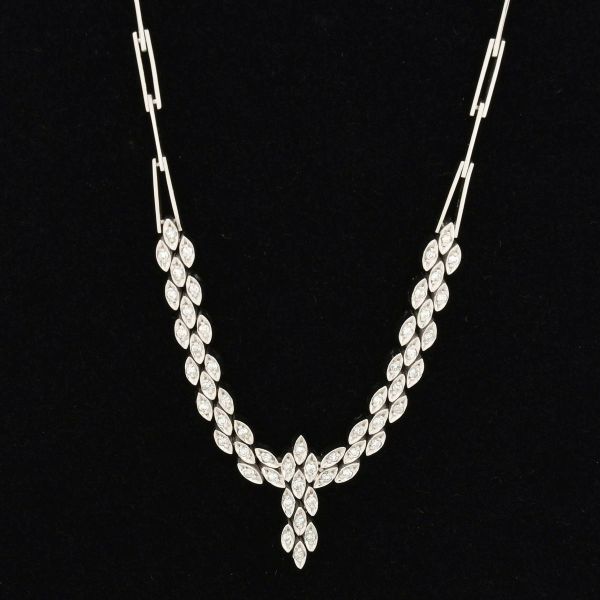 Gargantilha em ouro branco 18 k, decorada com aproximadamente 54 diamantes, formato silhueta em "V", estruturada com caimento simétrico que converge para um pinbente central, alongado. O colar é compo
