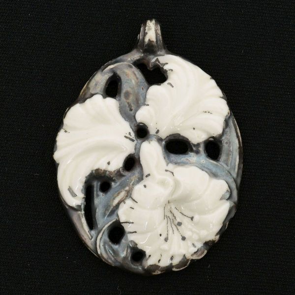 Rosenthal - Pendente em porcelana, design em relevo com folhas e flor na cor branca sobre fundo vazado na cor cinza. Medidas: 55 x 41 mm. Apresenta pequeno trincado no elo da corrente.